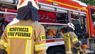 strażacy OPS na tle samochodu ratowniczo - gaśniczego z otwartymi skrytkami