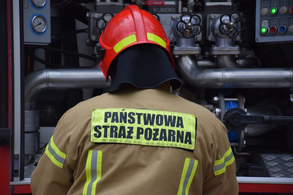 Strażak PSP stojący przy samochodzie ratowniczo - gaśniczym