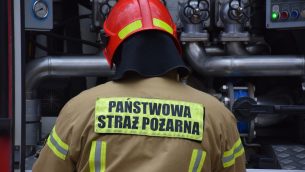 Strażak PSP stojący przy samochodzie ratowniczo - gaśniczym